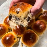 En person holder en friskbagt bolle med chokoladechips