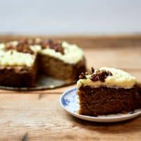 En skive kage med frosting og nødder på en tallerken